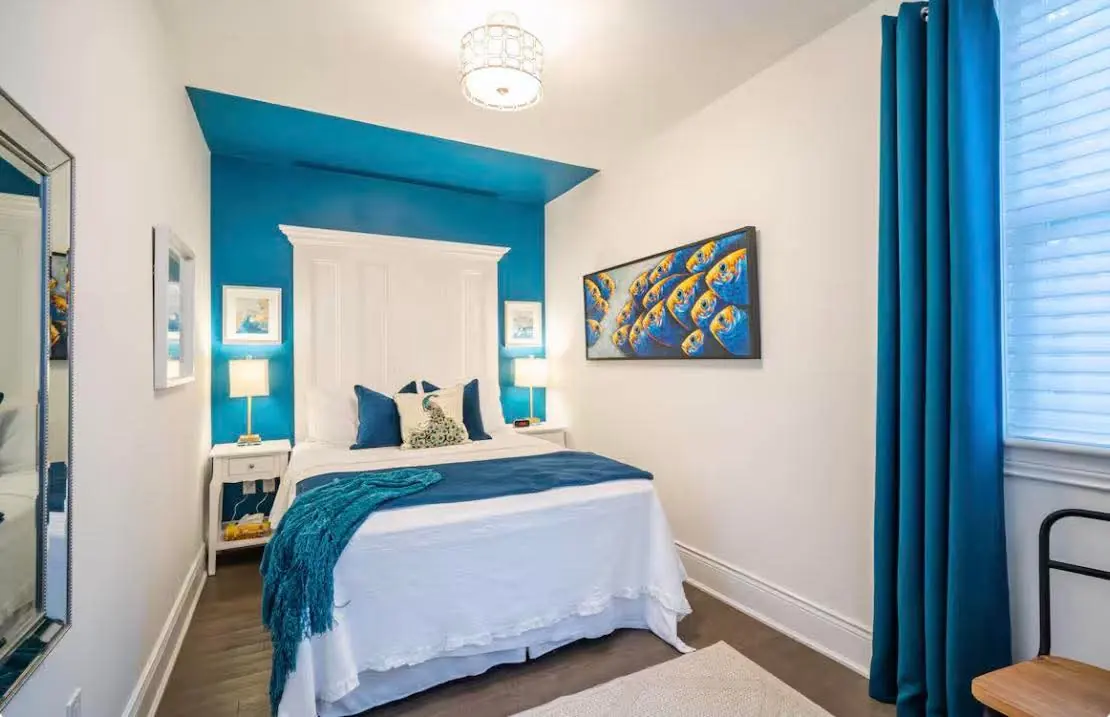 Neatly made bed with teal accents in a bright rental bedroom